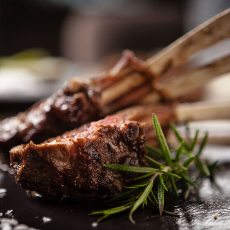 Grilled lamb chops served with a branch of rosemary on a black board
